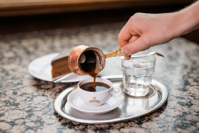 Café Schwarzenberg: Auf dem Tisch steht eine Sacher Torte und ein Türkischer Kaffee, der gerade eingeschenkt wird.